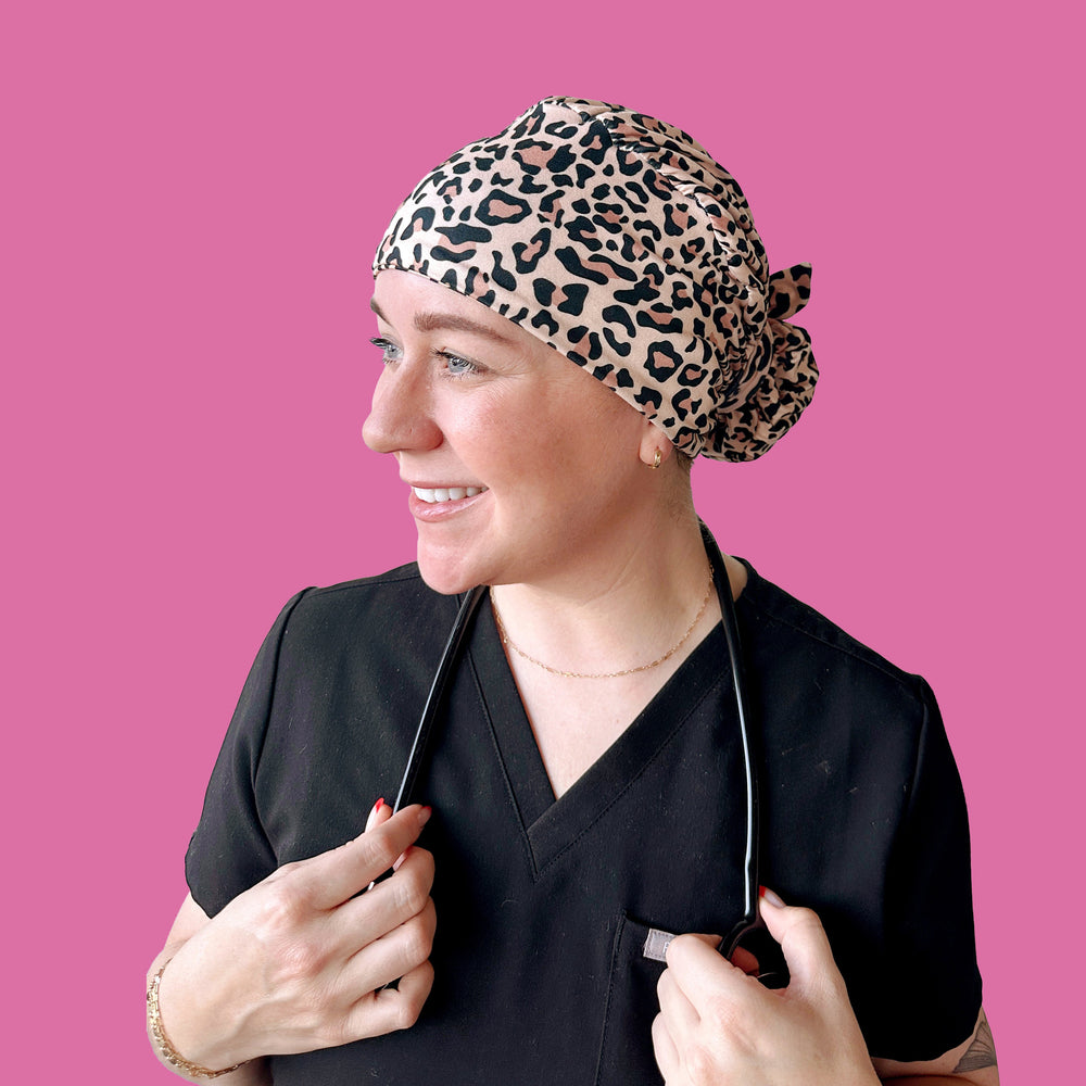 Person wearing a leopard print scrub cap against a pink background